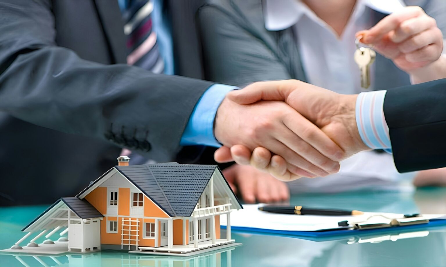 Handshake over a signed agreement with house keys and a model home